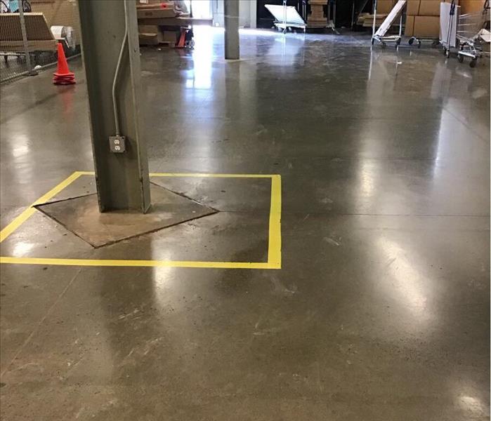 Dry concrete floor of a warehouse with a yellow square around a support beam in the background.