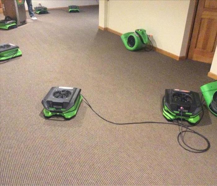 Dry grey carpet with green air movers spread out on the floor.