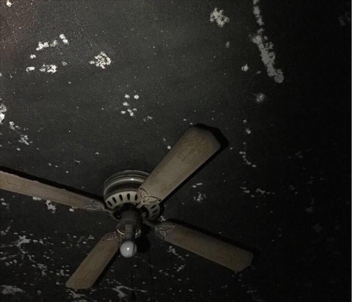 A white ceiling fan covered in soot.