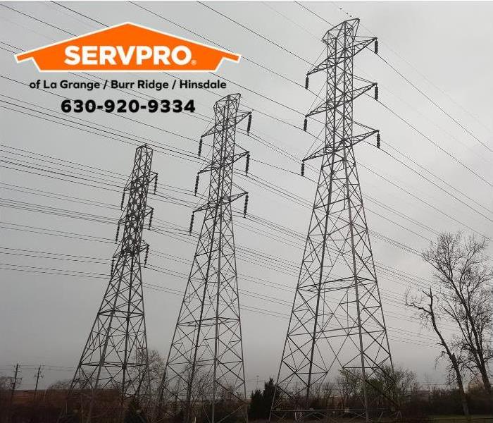 Three tall power towers with several power lines with grey sky in the background.