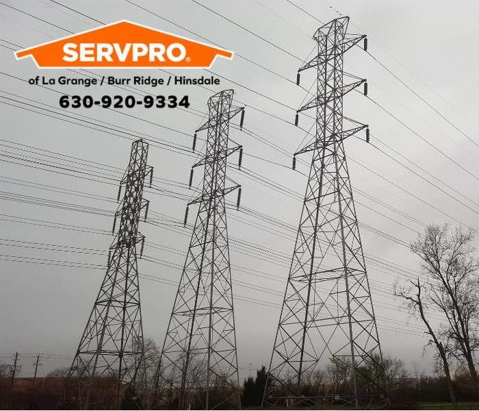 Three tall power towers with several power lines with a grey sky in the background.